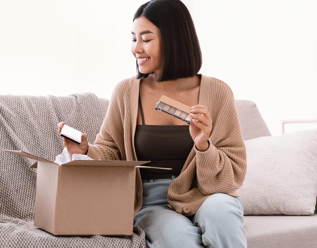 A woman is opening her online makeup order.