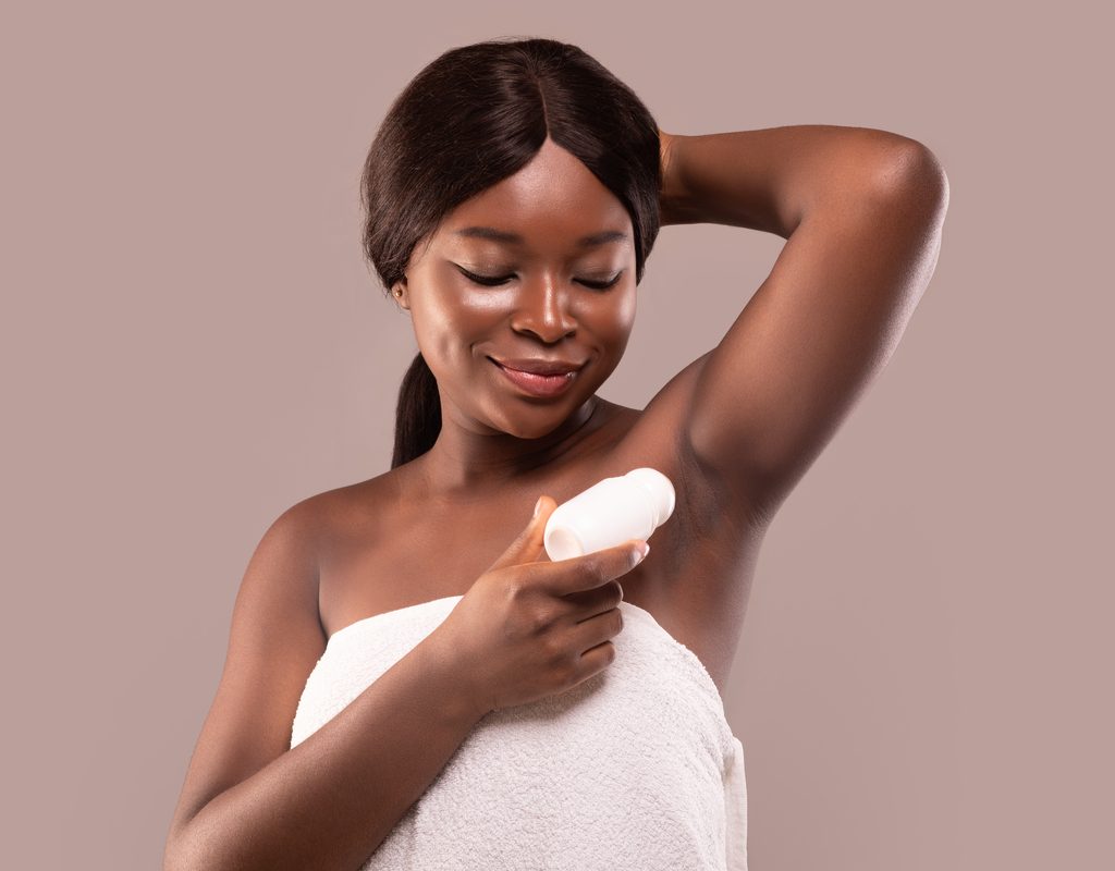 A woman putting on deodorant.