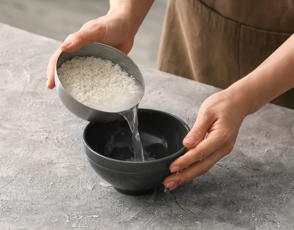 A woman pouring the water out of a rice and water mixture.
