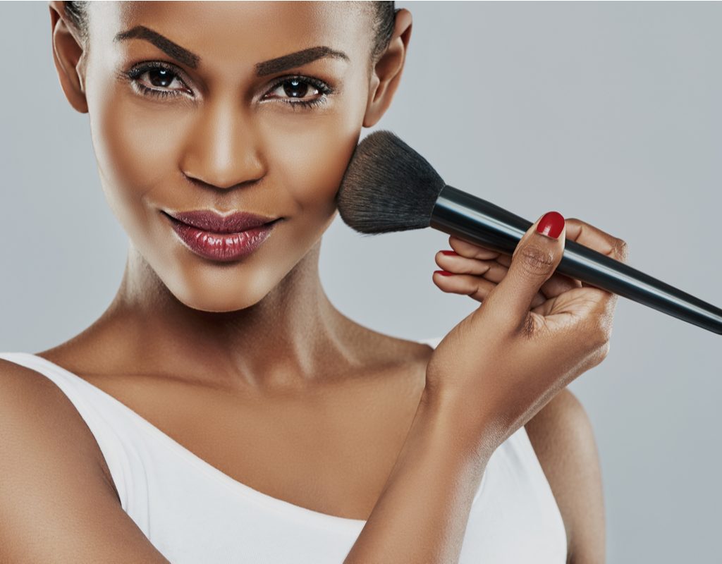 A Black woman applying makeup.
