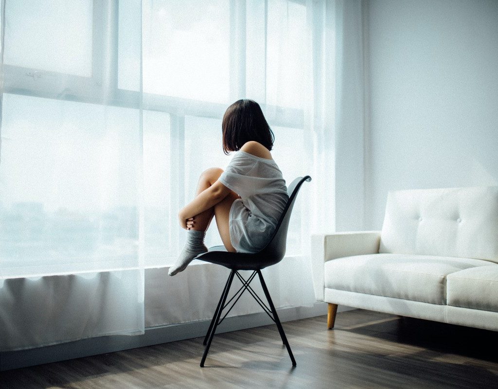 woman looking out window while sitting in chair