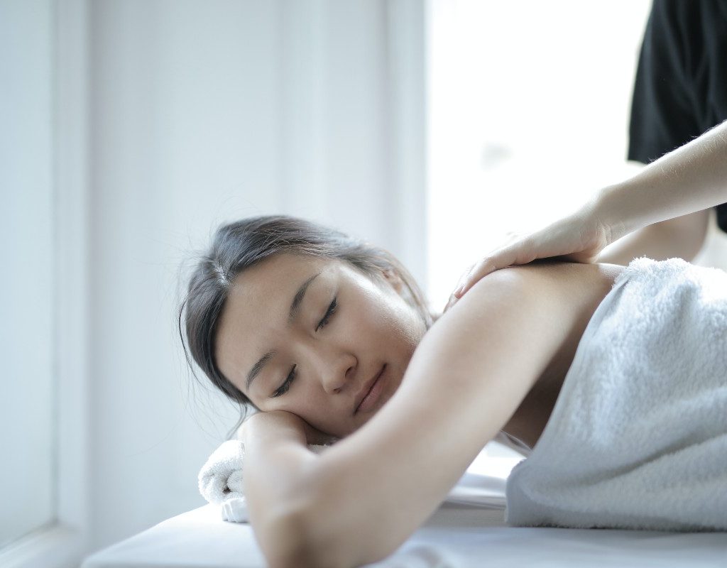 woman receiving upper body treatment while lying in a towel