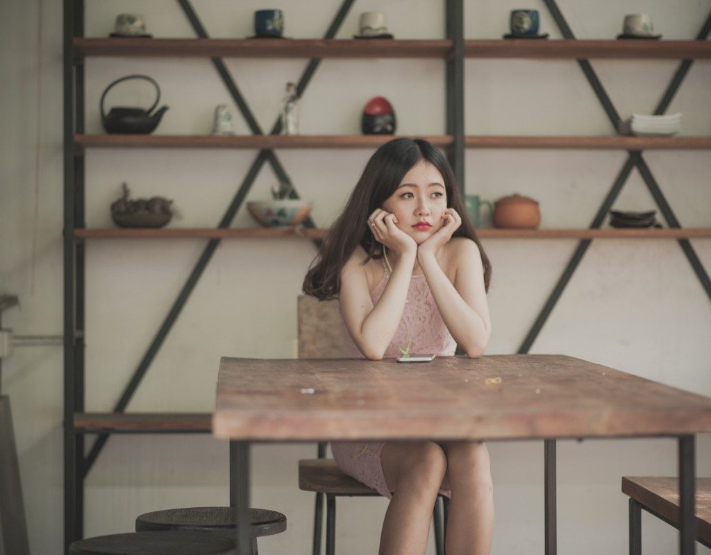 woman in pink dress sitting at a wooden table