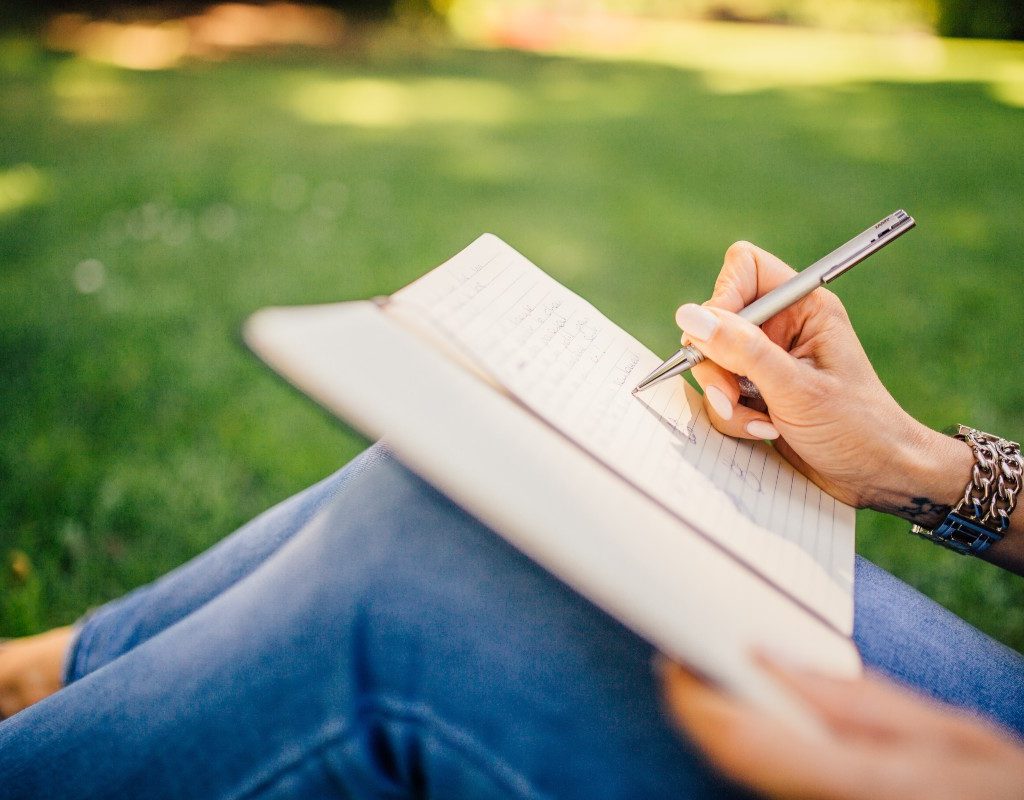 a personal journaling with a notebook and pen while sitting outside