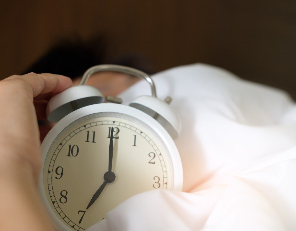 a standard alarm clock in a bed with white sheets