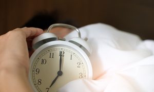 a standard alarm clock in a bed with white sheets