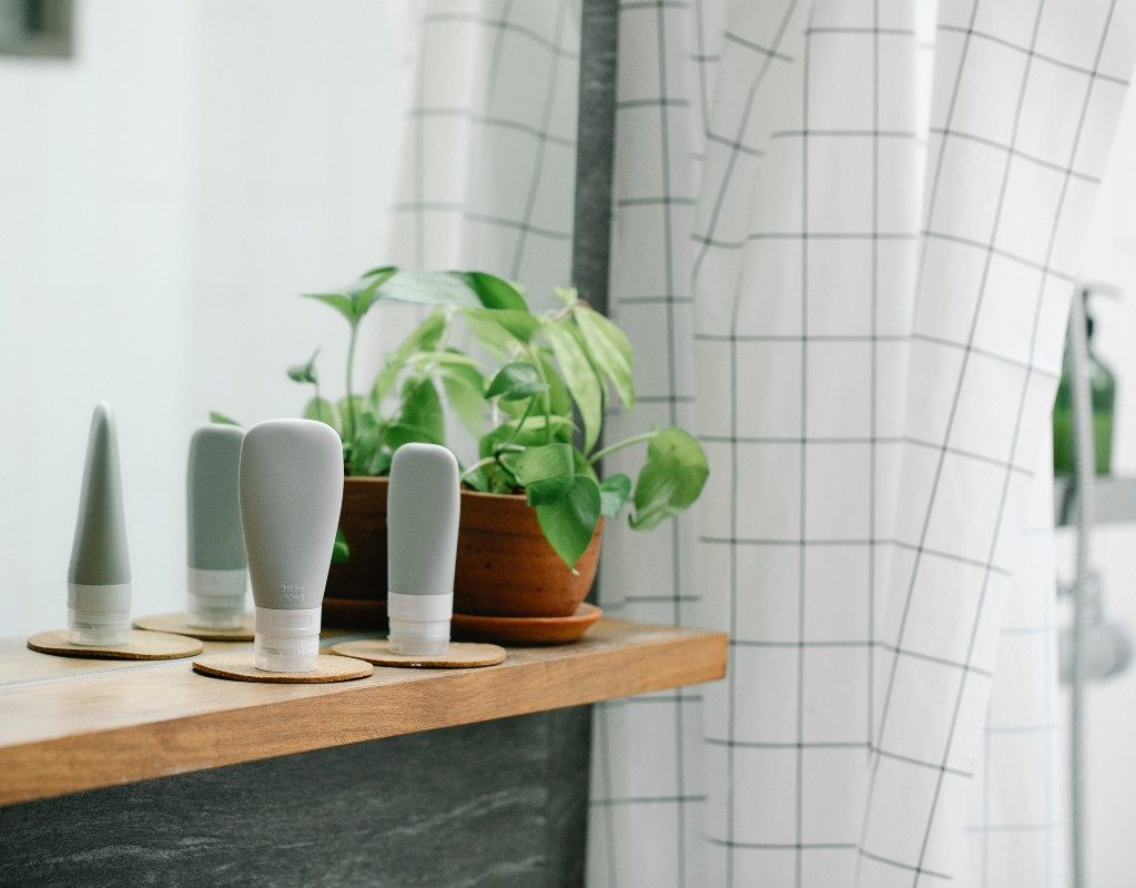 a bathroom counter with three unbranded creams and plant