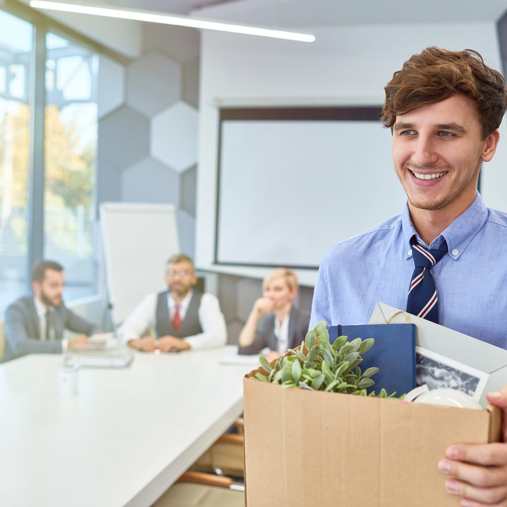 Happy man leaving office with packed box