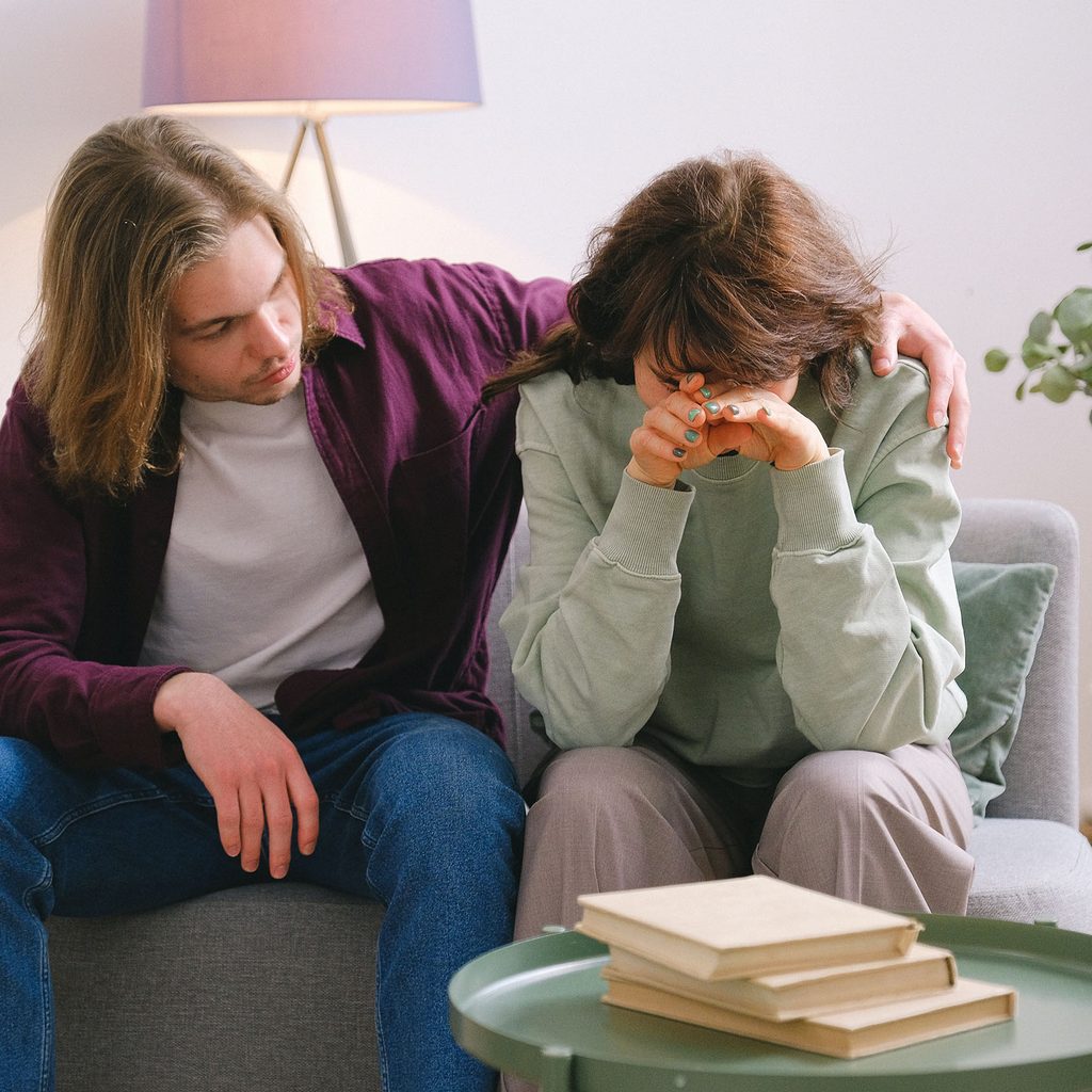 Man comforting a woman on a couch