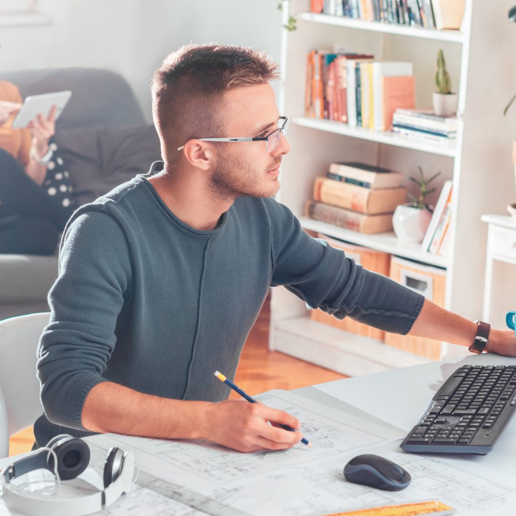 Man working at home office with computer screen at eye level