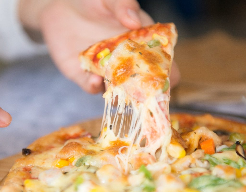 a person taking a slice of pizza with pepper on top