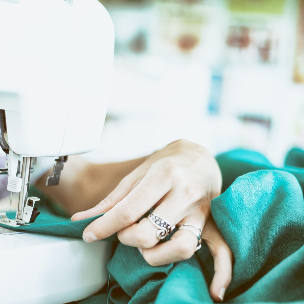 Person sewing turquoise fabric