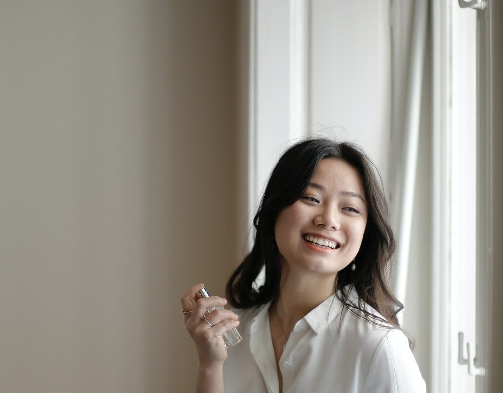 A woman spraying on perfume.