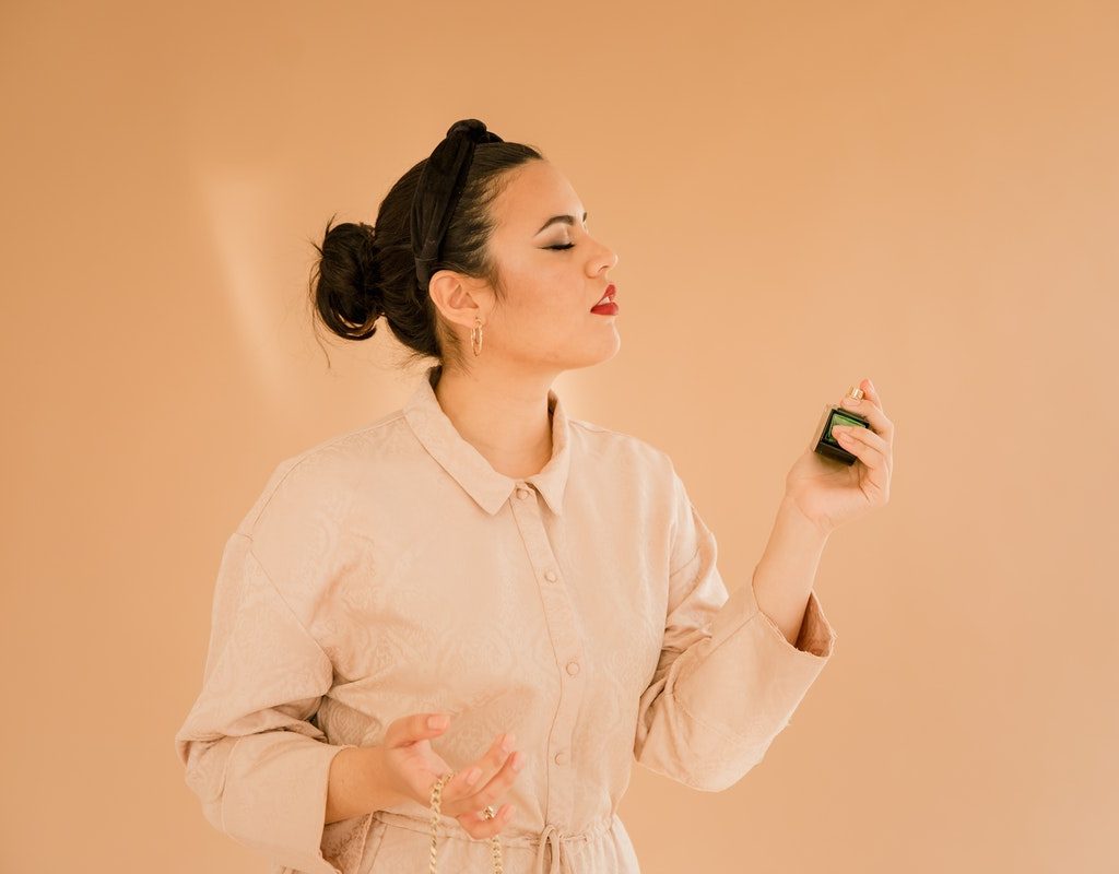 A woman putting on fragrance.