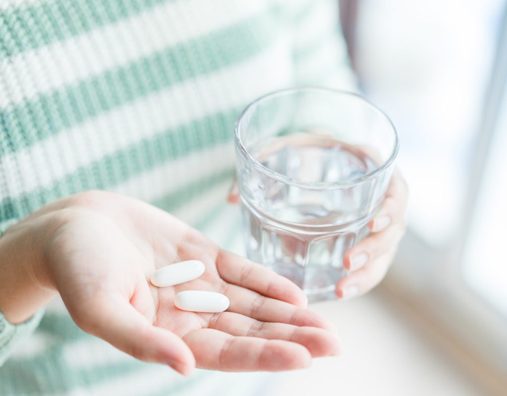 A woman taking a few supplements.