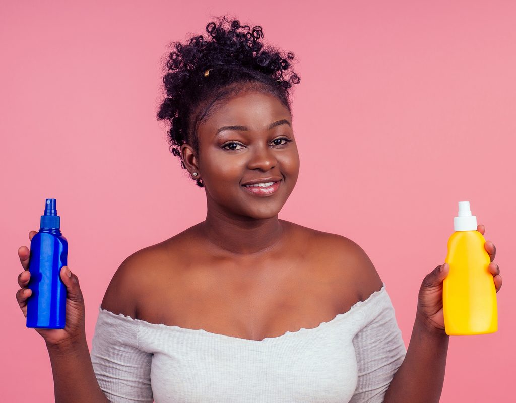 A Black woman holding beauty products in her hands.