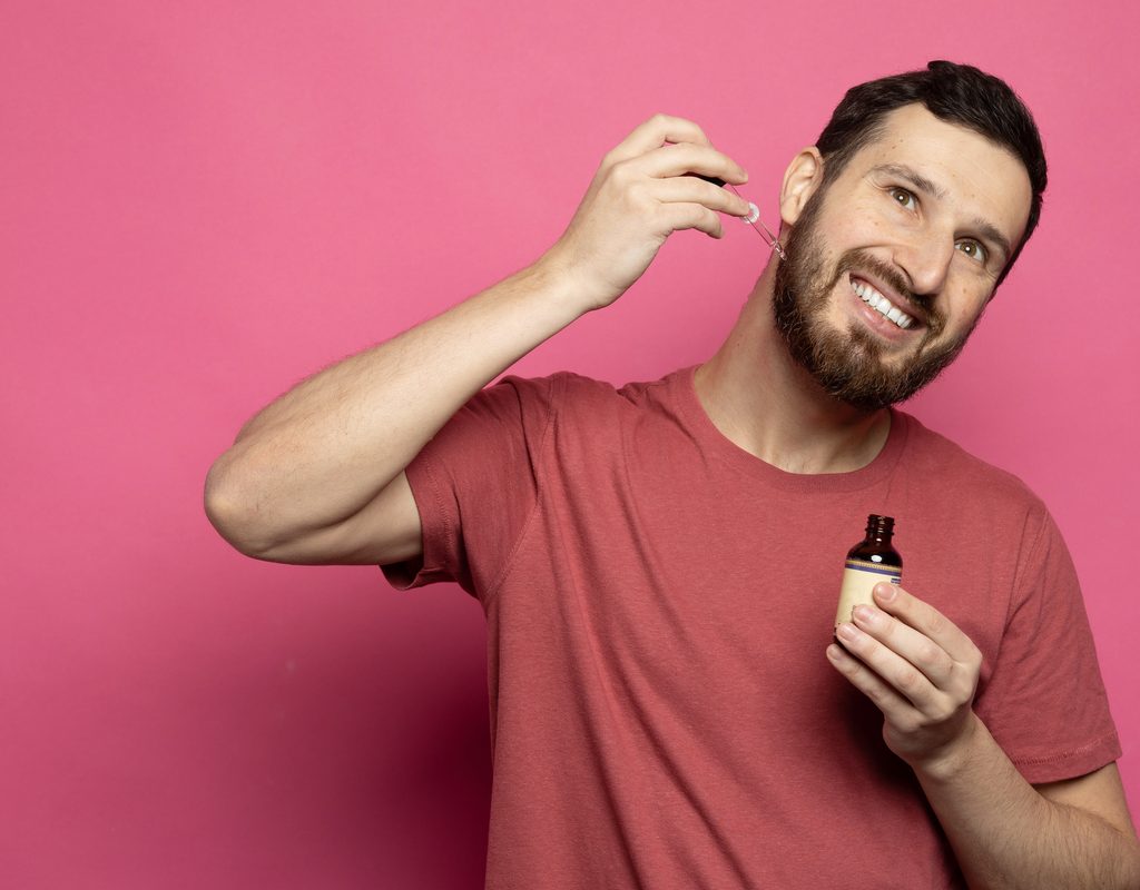 A man putting beard oil on his face.