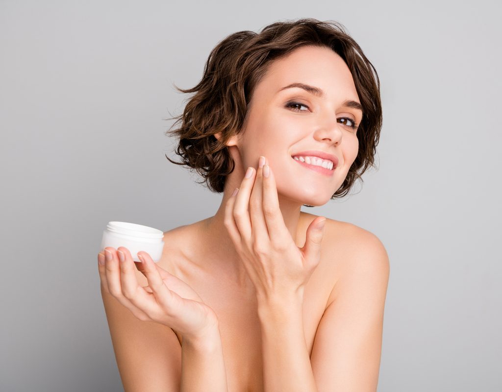 A woman applying a cream to her face.