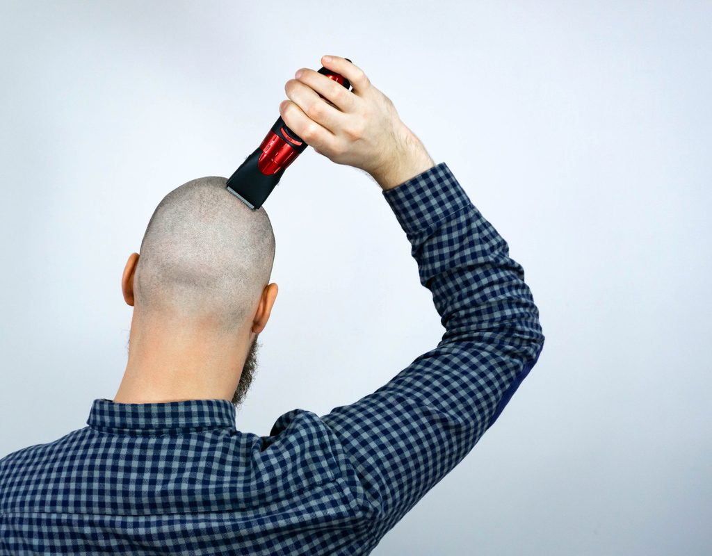 A man shaving his head clippers.