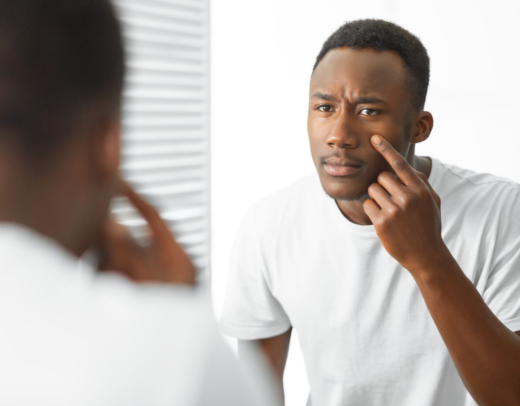 A man looking at his face in a mirror.