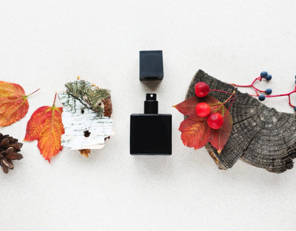 A bottle of fragrance surrounded by fall-themed items.