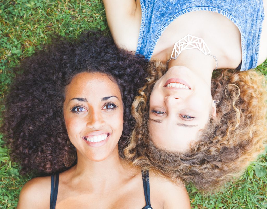 Two women with curly hair laying on the ground.