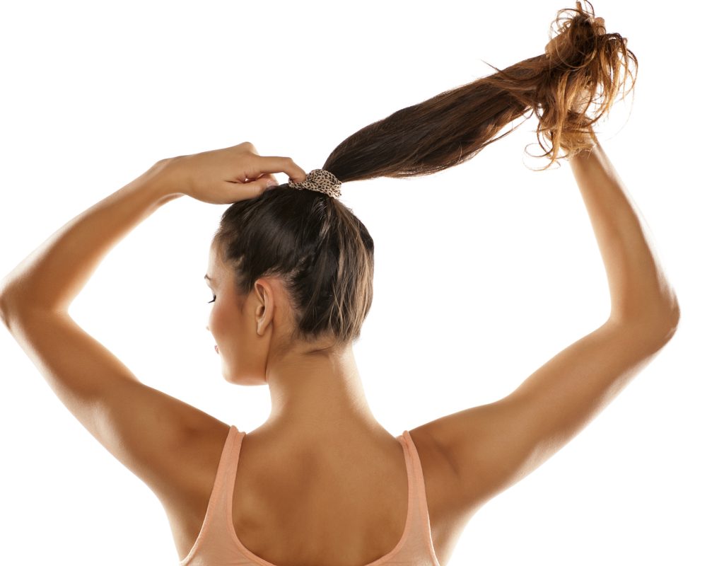 A woman putting her hair in a ponytail.
