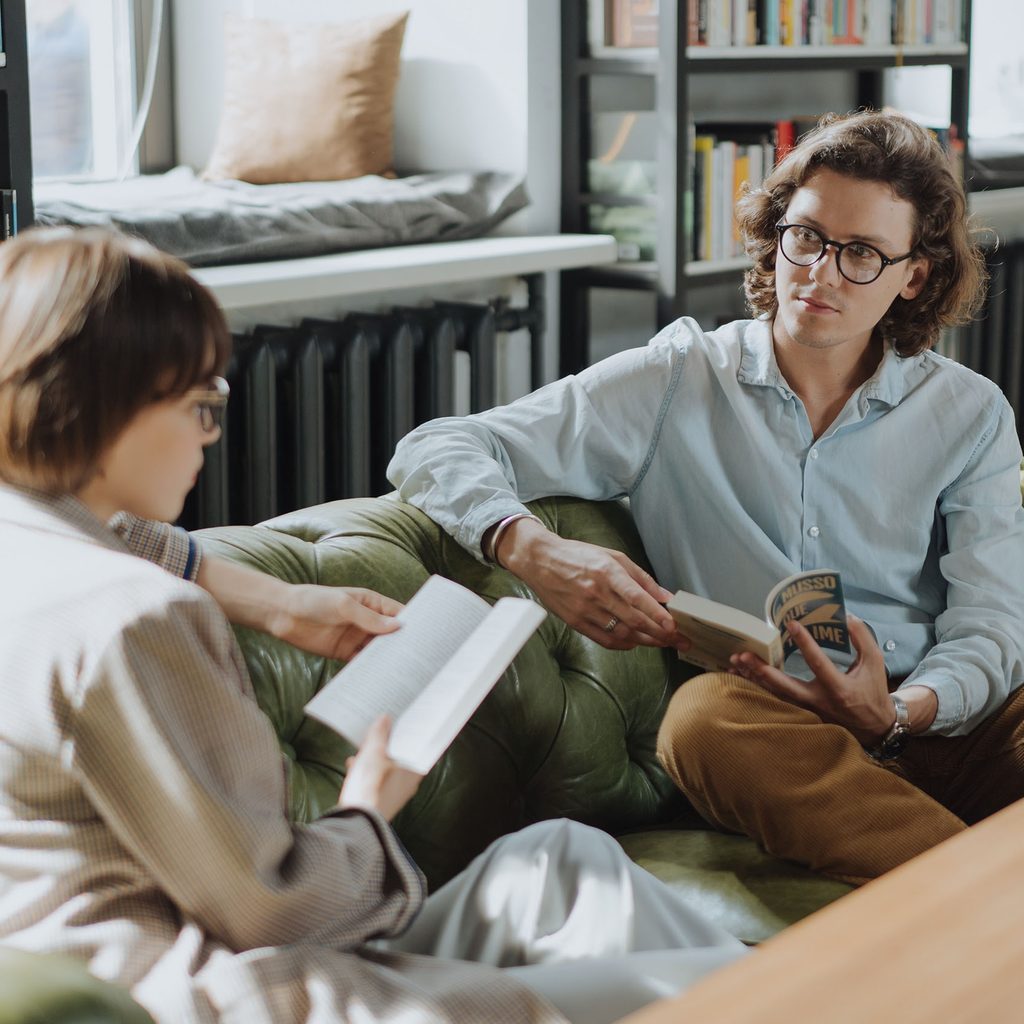 Two people reading and discussing on a couch