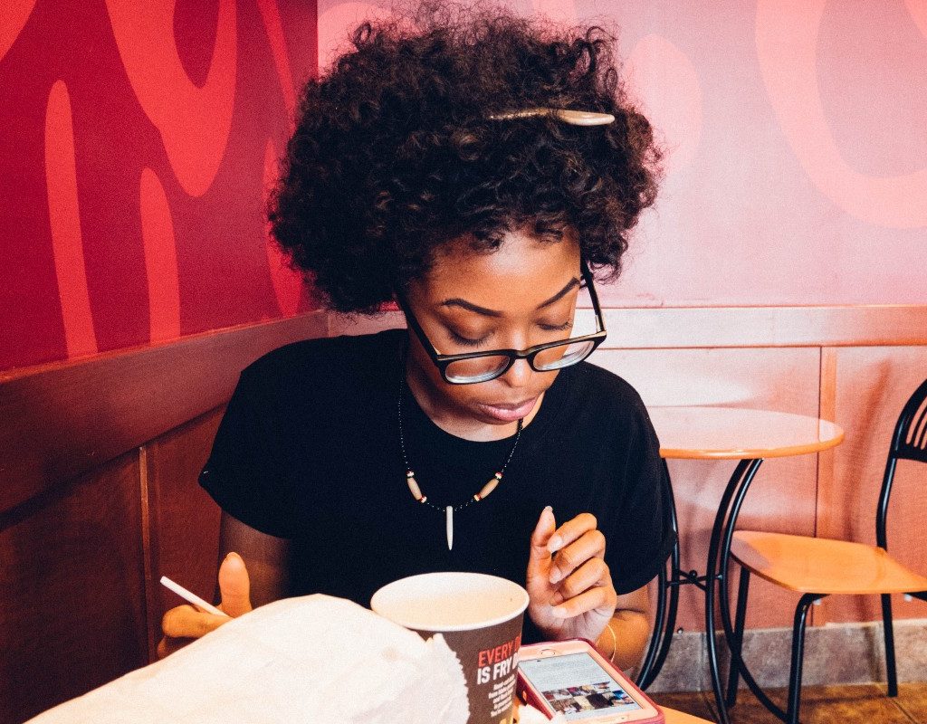 woman in restaurant eating while looking at phone