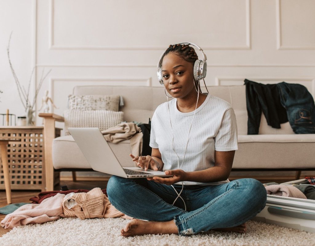 a woman sitting on the floor listening to music while on the computer