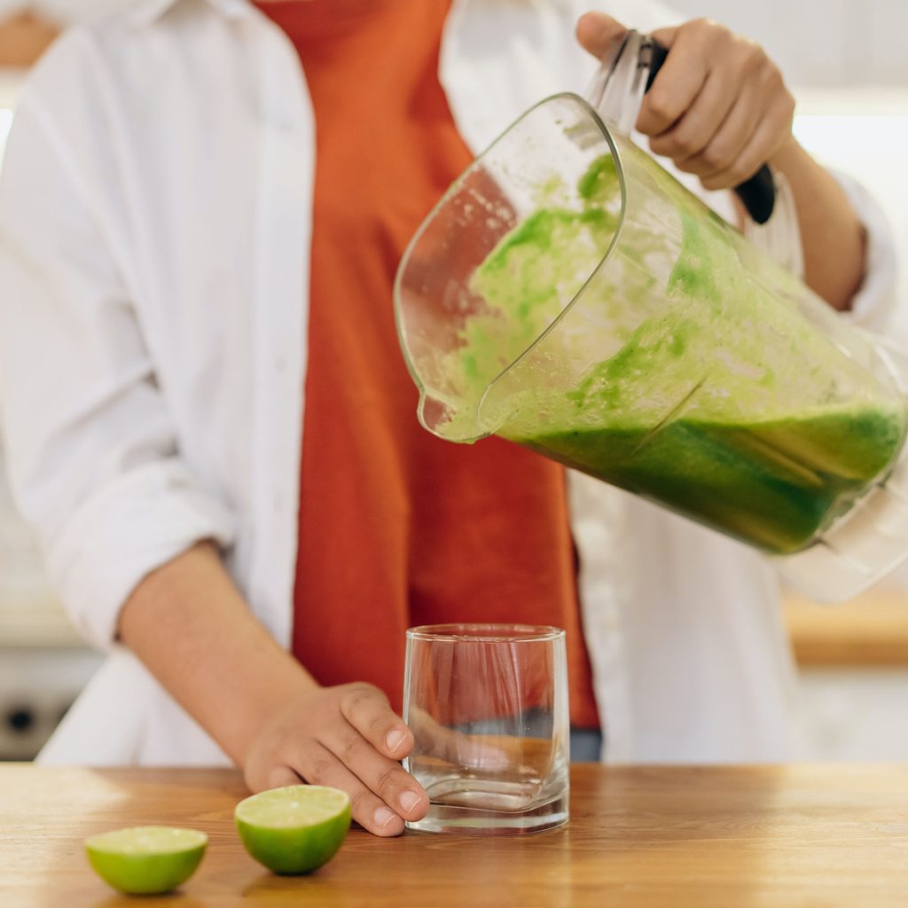 Woman pouring green smoothie into a cup
