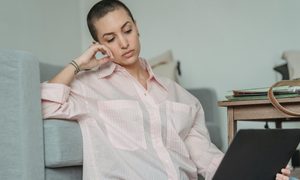 tired woman sitting in a chair looking at a computer
