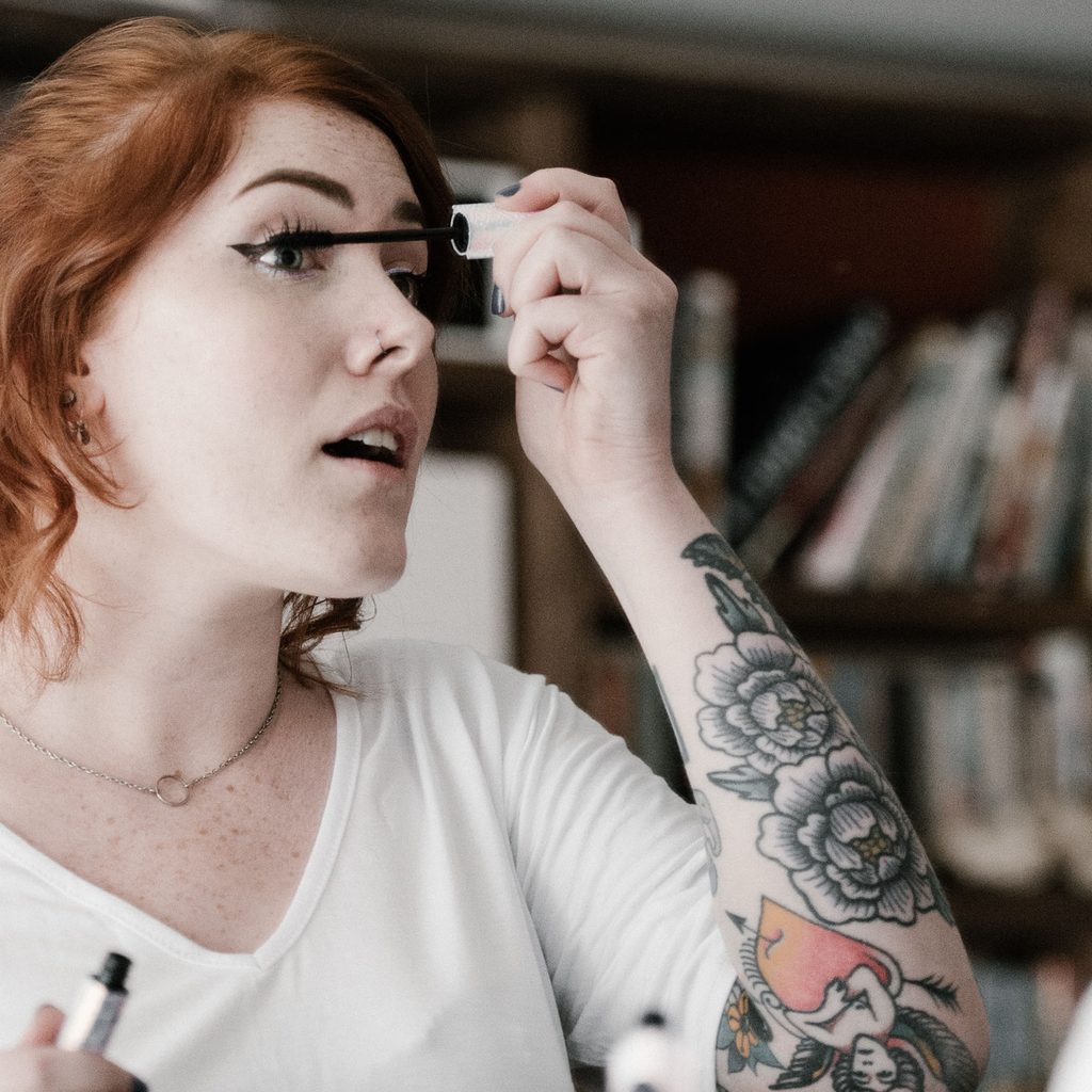 Woman with tattoos applying mascara