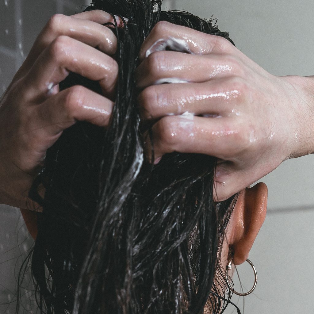 Brown haired woman washing her hair in the shower