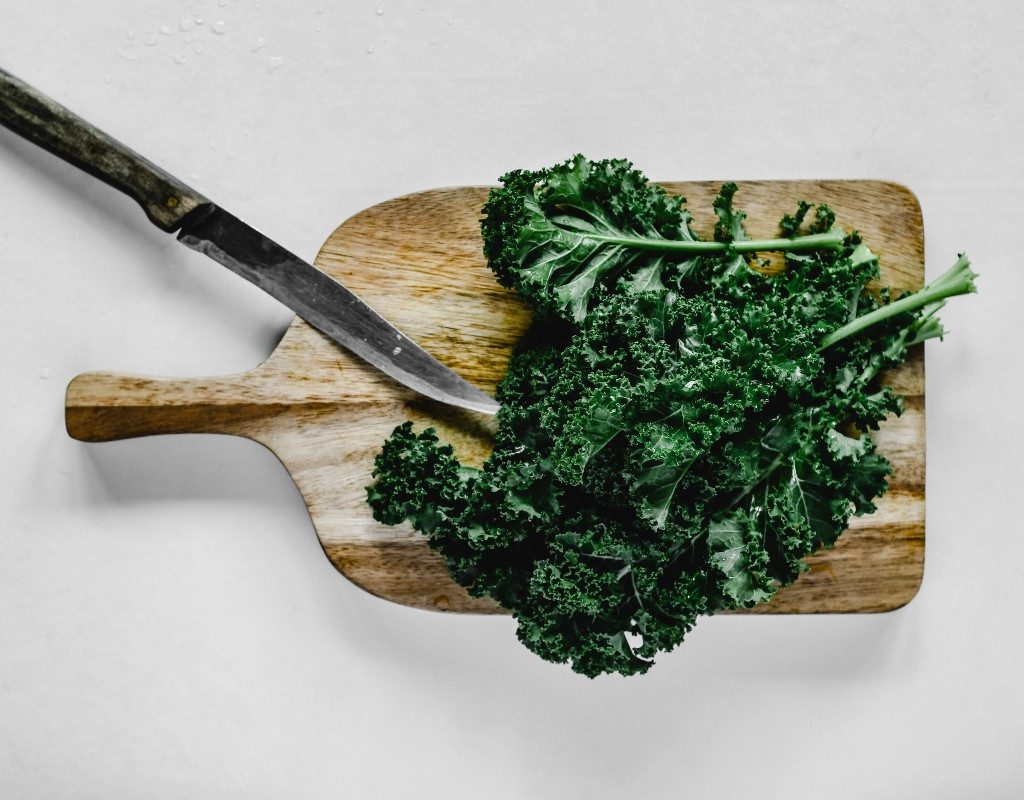 kale on a cutting board with a knife