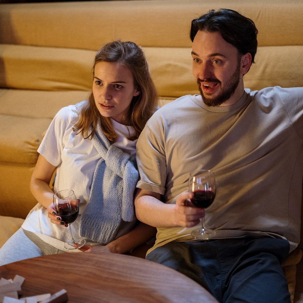 Man and woman watching tv with wine