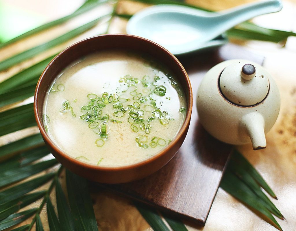 a small bowl of miso soup next to a teapot