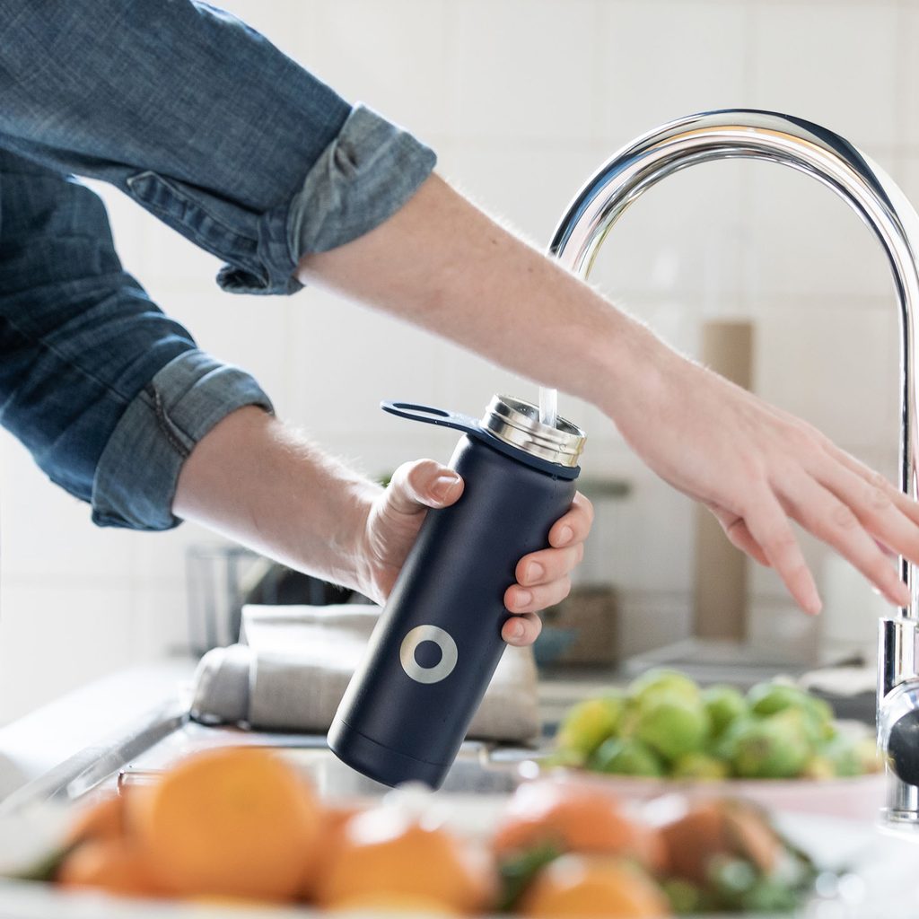 Person filling a reusable water bottle in the sink