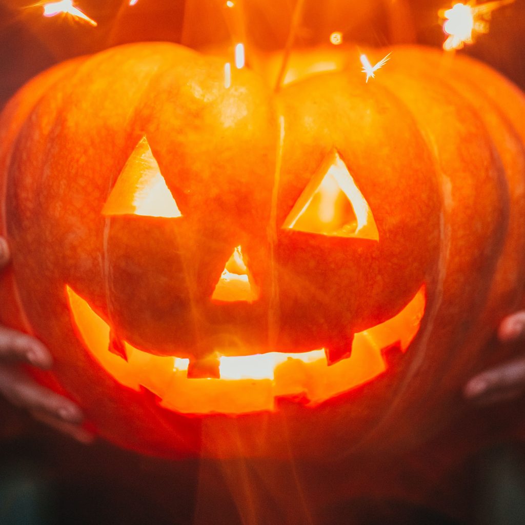 Person holding a lit jack-o-lantern