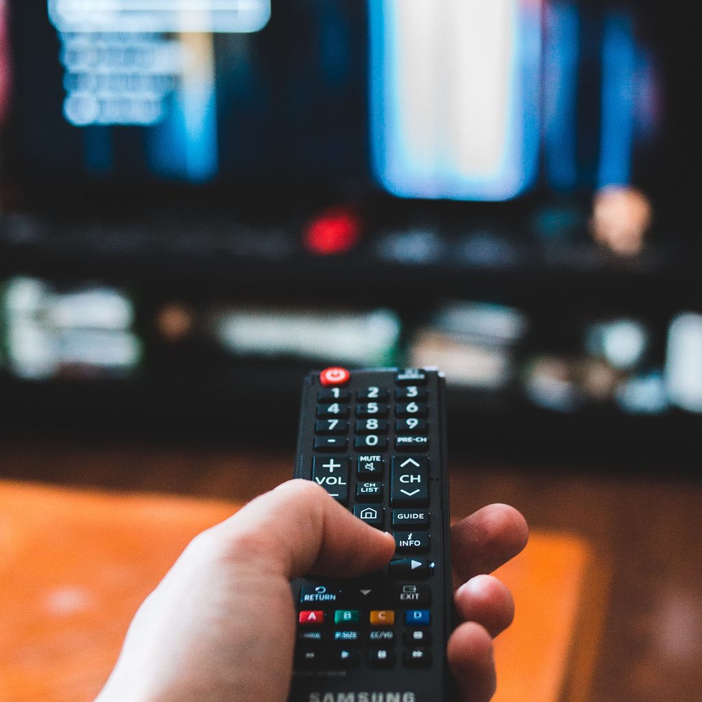 Person holding a remote watching tv