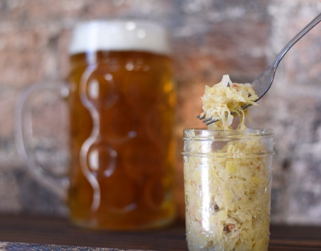 someone spooning sauerkraut out of a mason jar