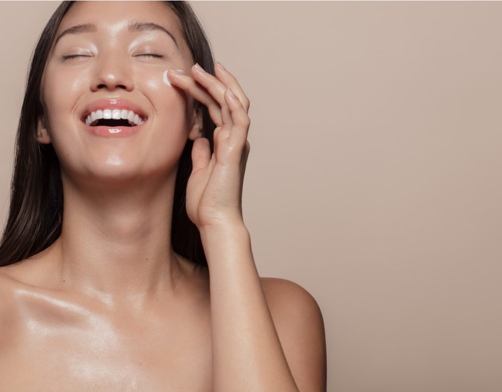 A woman putting on face cream.