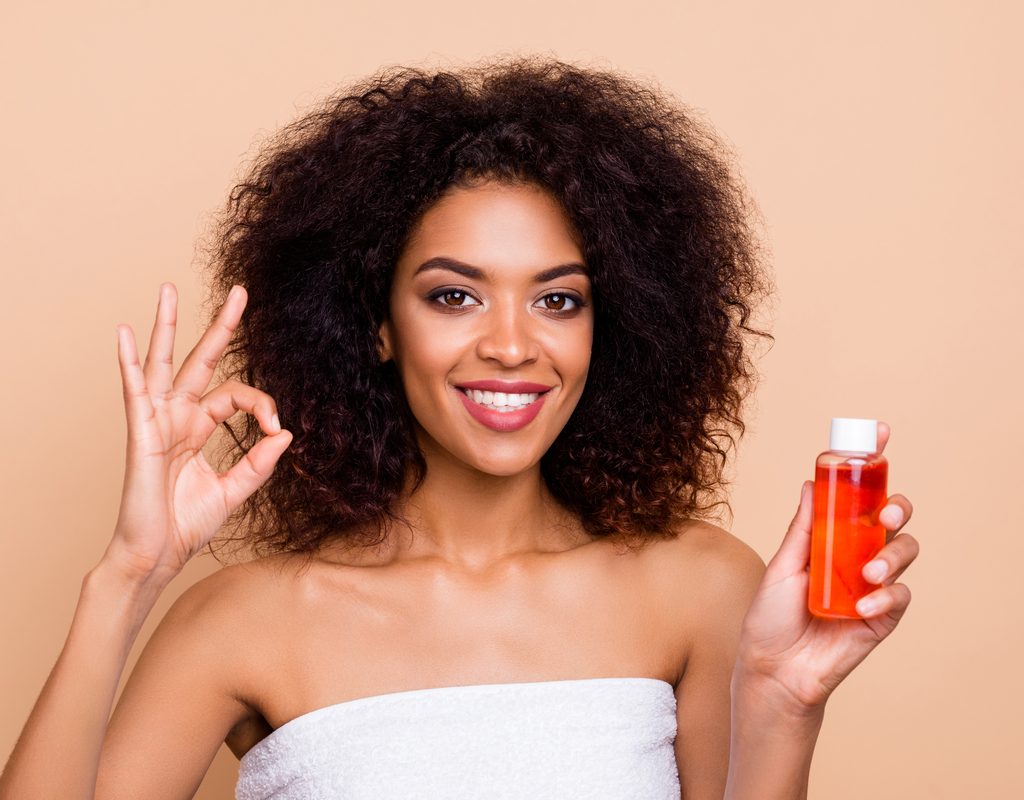 A woman holding a bottle of hair oil.