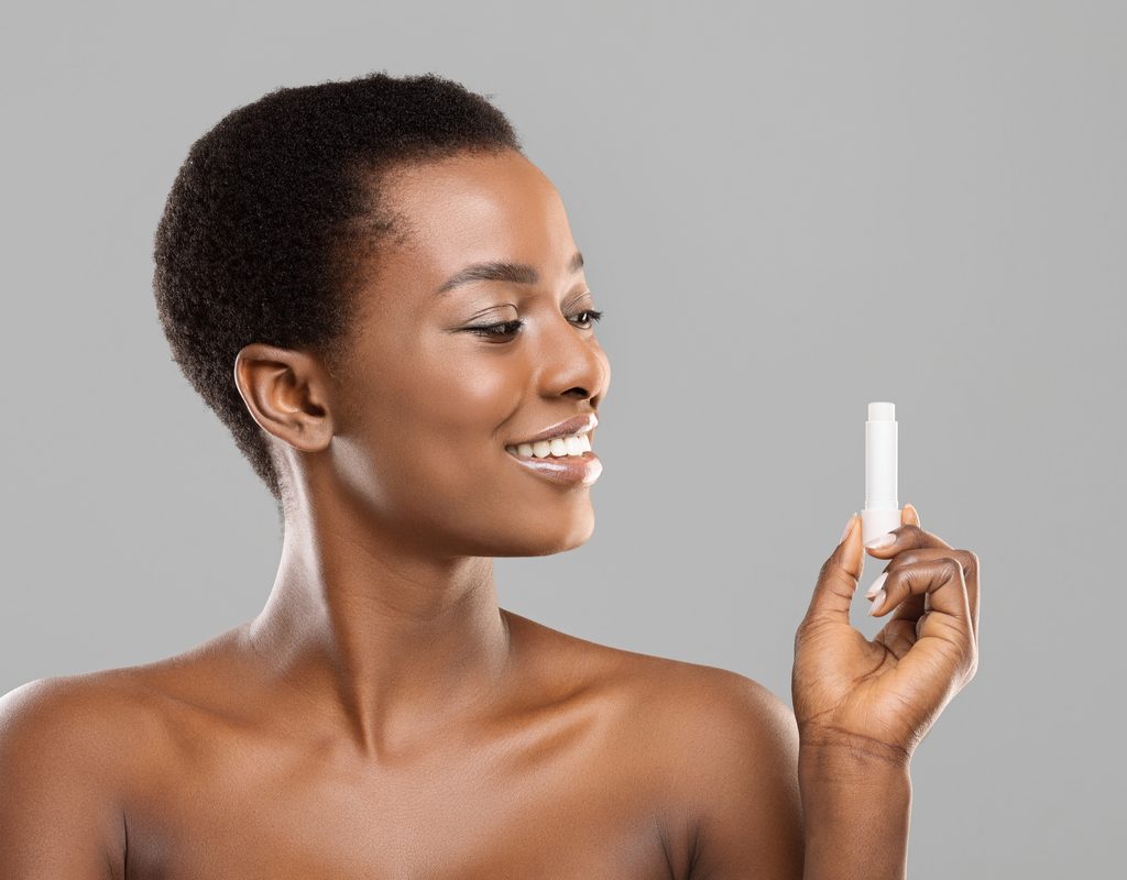 A woman holding up a lip balm.
