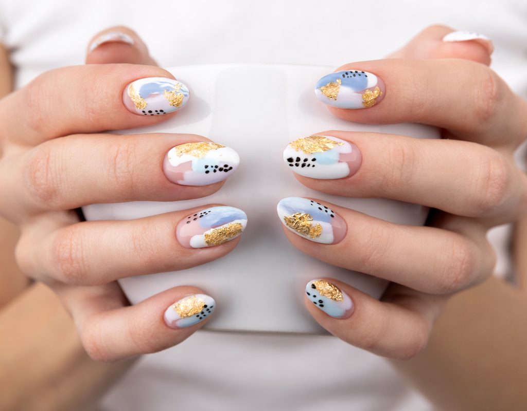 Nails with fun nail art holding a cup.