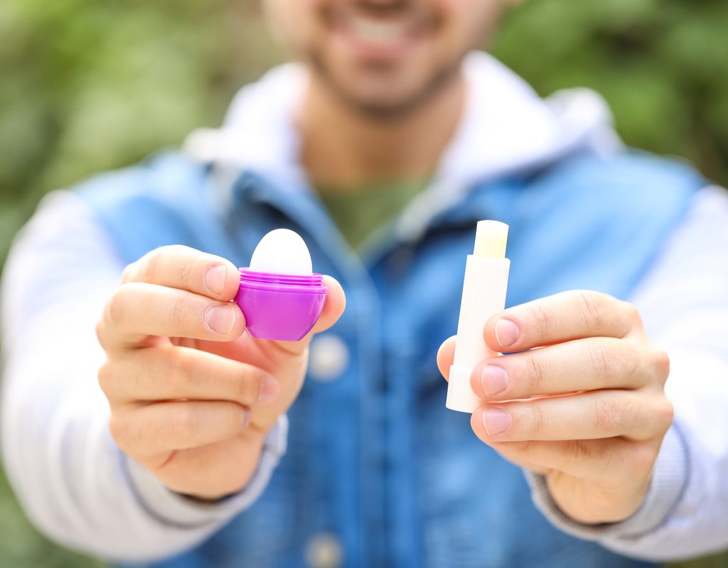 A man holding up two different lip balms.