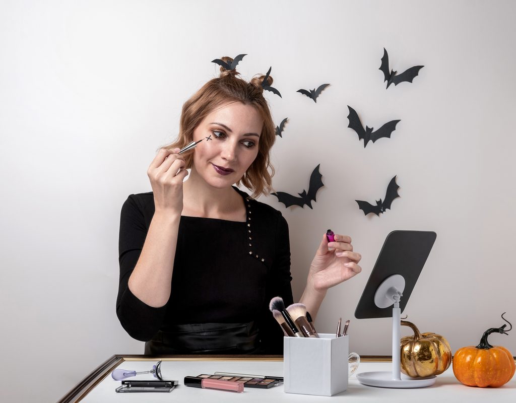 A woman doing her Halloween makeup.