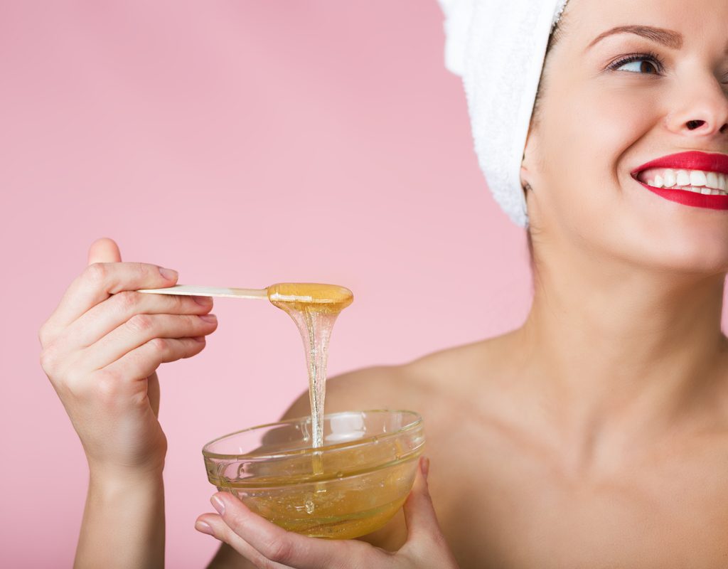 A woman holding a bowl of sugar paste for hair removal.