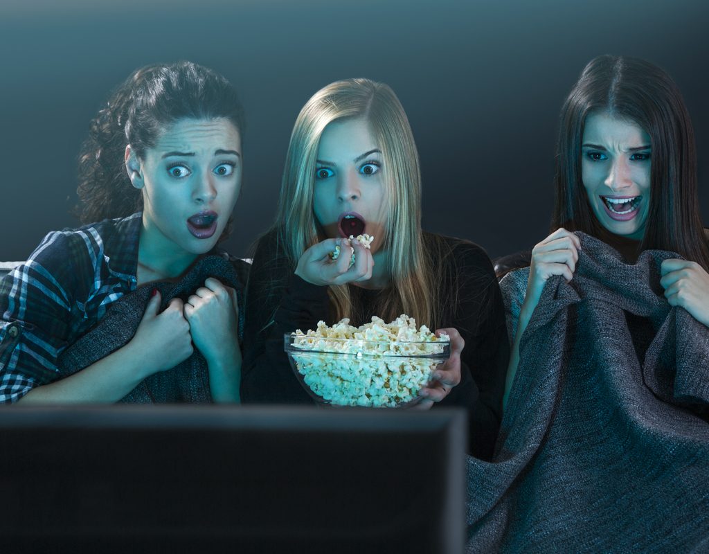 Three women watching a scary movie.