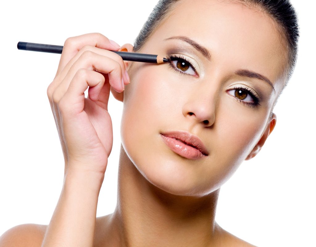 A woman putting on eye makeup.